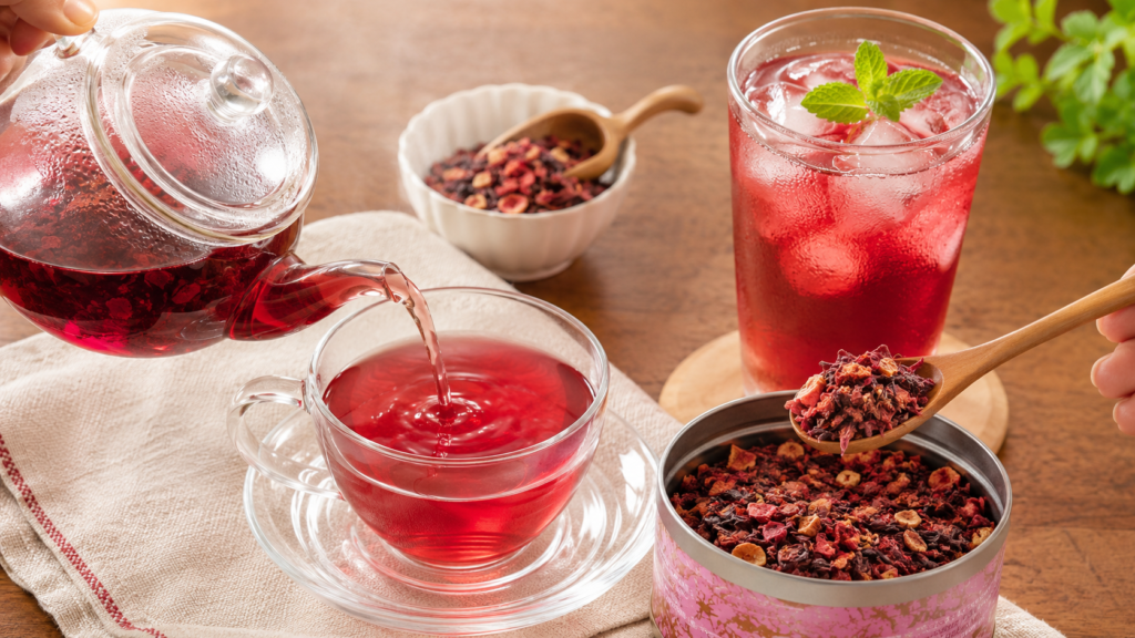 A realistic tabletop scene showing freshly brewed hot red herbal tea being poured into a glass cup alongside a refreshing iced berry herbal tea with ice, highlighting two ways to enjoy fruit herbal tea.